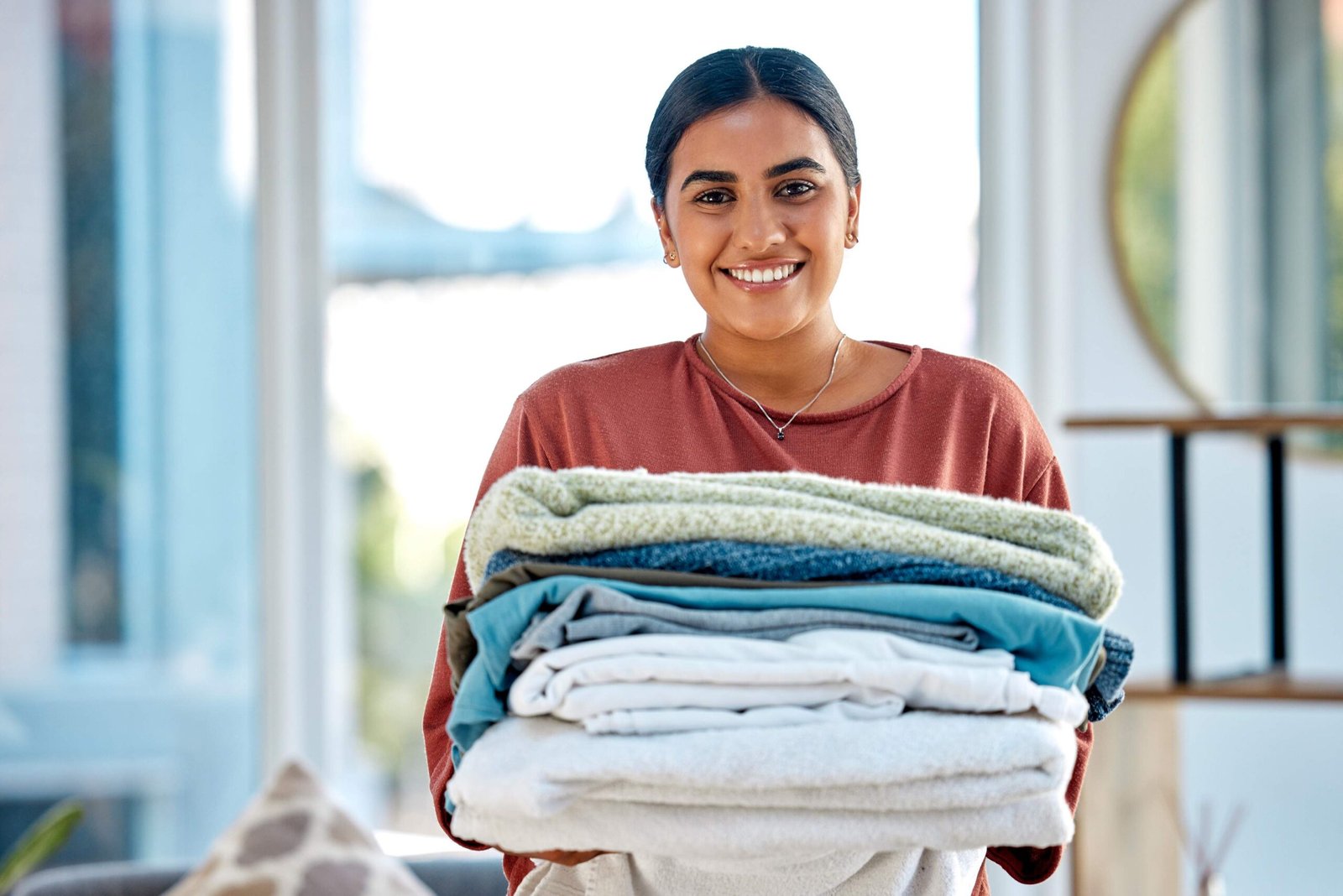 Portrait, cleaning or woman with laundry or happy smile after washing clothes or towels in cleaning services. Hospitality, hotel or face of Indian cleaner working at a airbnb, house or home in Mumbai.